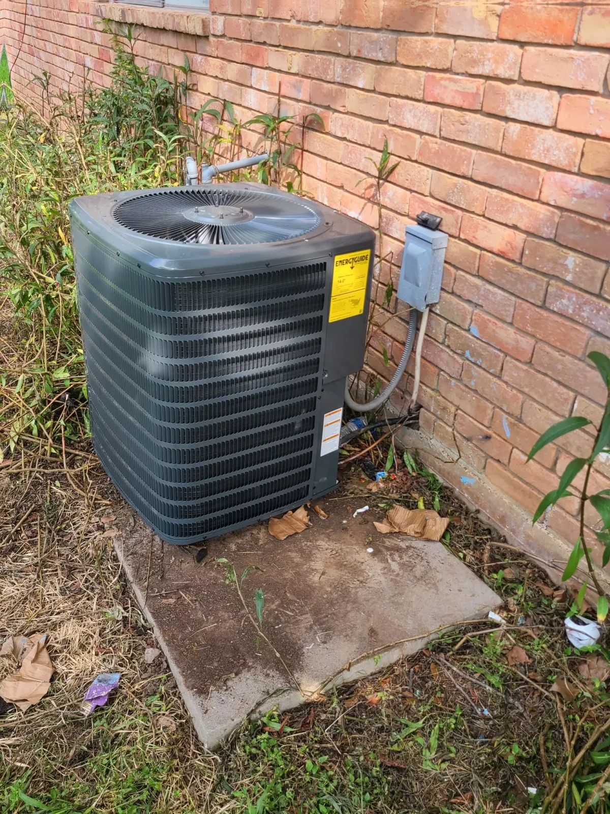 AC residential condenser on brick home — Pearland HVAC repair